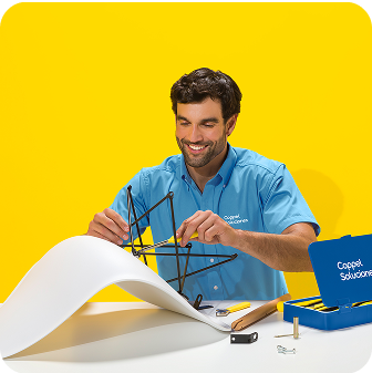 Un solucionador armando una silla sobre una mesa contra un fondo amarillo brillante.