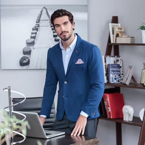 Modelo masculino con saco azul de vestir y pañuelo para traje en el pecho, con camisa azul claro de vestir debajo. Pulsa aquí para ver más prendas de invierno de Wallstreet, abre en pestaña nueva.