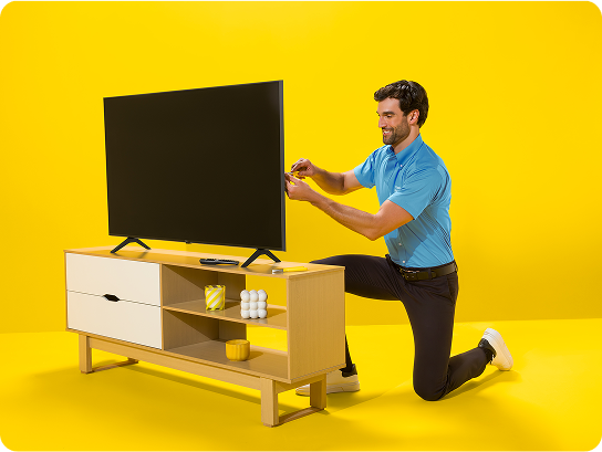 Una sololucionadora examina una television sobre una mesa contra un fondo amarillo brillante.