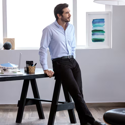 Modelo masculino con camisa azul claro formal de manga larga, pantalón negro de vestir y cinturón negro. Pulsa aquí para elegir tu camisa Wallstreet, abre en pestaña nueva.