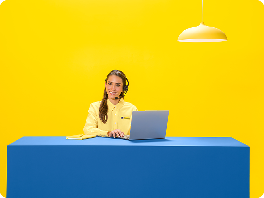 Una solucionadora examina una licuadora sobre una mesa contra un fondo amarillo brillante.