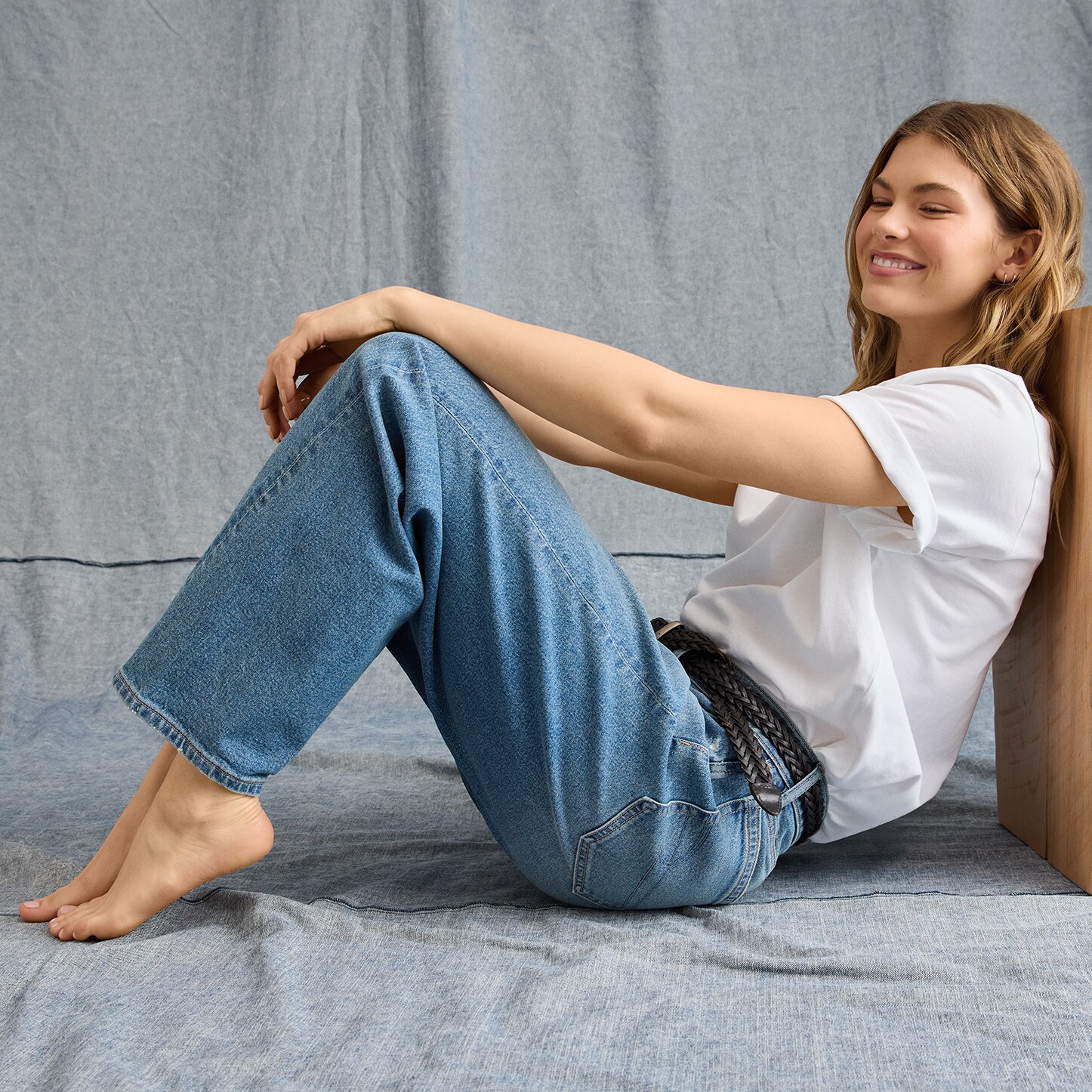 Modelo mujer usando blusa blanca y pantalón azul de mezclilla. Pulsa aquí para ver ropa para mujer de la marca American Eagle.